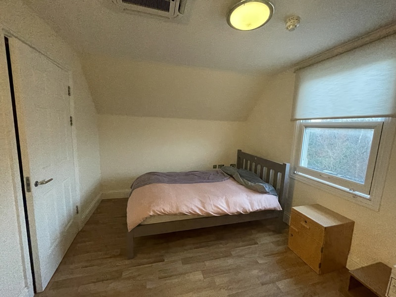 Bedroom at Kemble House with a double bed, wooden chest of drawers and a window with a blind
