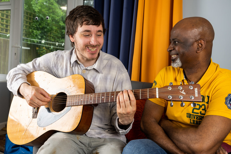 Playing an acoustic guitar together in the lounge at Ty Newydd