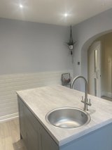 Kitchen at Maple Leaf Lodge with a grey island, round sink, white metro tiles and an arched doorway