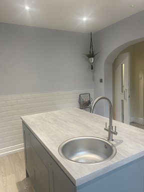 Kitchen at Maple Leaf Lodge with a grey island, round sink, white metro tiles and an arched doorway