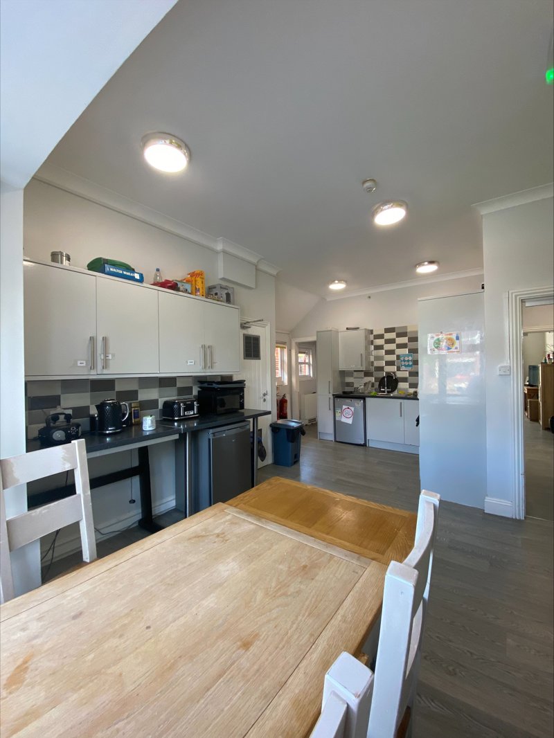 Kitchen and dining area at Eilat with white units, grey tiled splashback and a wooden table