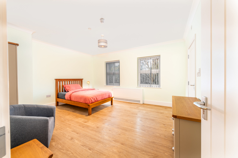 Bedroom at Church Road with a wooden bed, coral bedding and an armchair