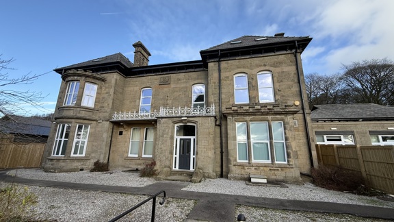 Stone-built Victorian manor housing Oaklands Manor, with bay windows, an ornate balcony and a central entrance