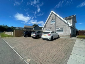 Exterior of Rosewood, a grey-rendered house with an apex gable and a block-paved parking area
