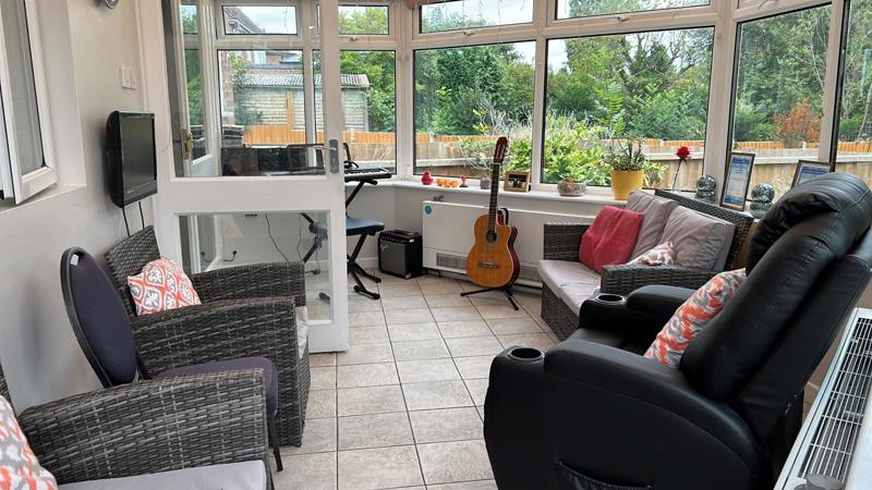 Conservatory seating area at Chesterwood with rattan chairs, recliners and a guitar