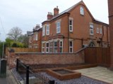 Front exterior of Lester Court, a red-brick Victorian house with bay windows and a walled front garden