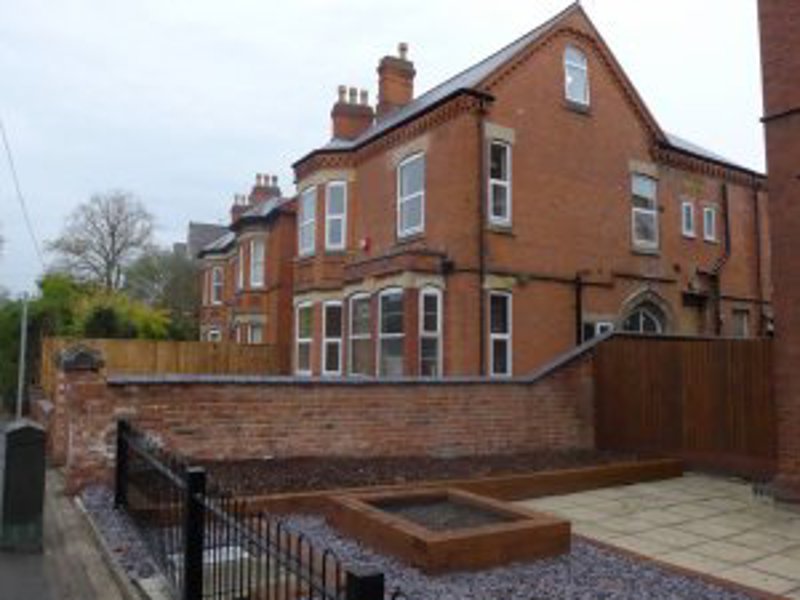 Front exterior of Lester Court, a red-brick Victorian house with bay windows and a walled front garden