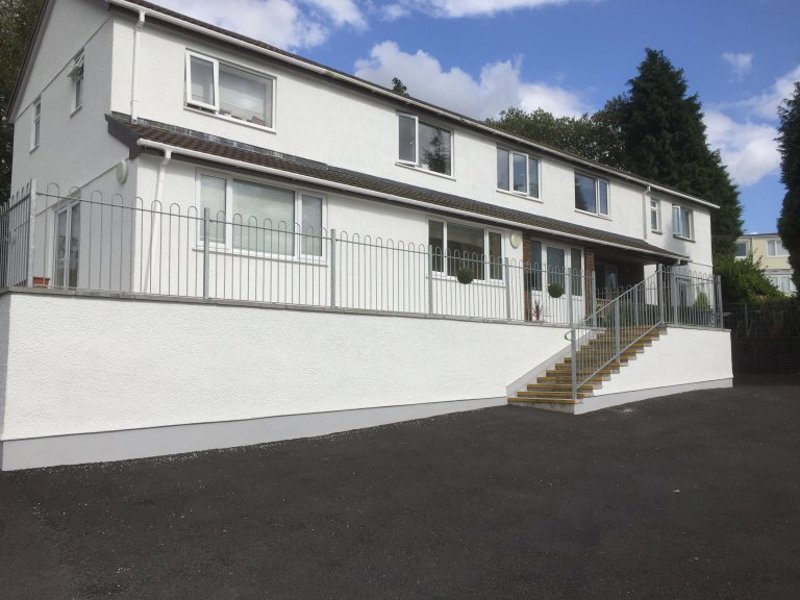 Front exterior of Grove View, a white rendered house with a railed terrace, steps and a tarmac drive