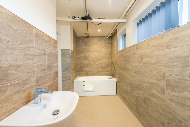 Accessible bathroom at Church Road with a walk-in bath, ceiling hoist track and basin