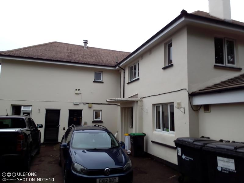 Rear exterior of Chepstow House, a cream two-storey building with parked cars and a tarmac driveway