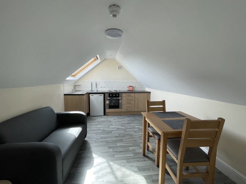 Loft studio flat at Birchwood House with a sofa, kitchenette and dining table under a sloped ceiling