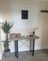 Hallway at Ty Camlas with a console table, a Welcome Home letterboard sign, a tall yucca plant and wall coat hooks