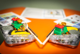Brightly coloured objects in a tin on a bright orange desk