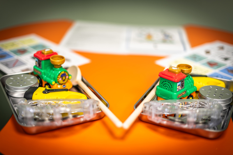 Brightly coloured objects in a tin on a bright orange desk