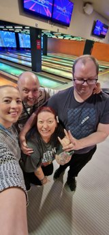 Four residents and staff smiling together at a bowling alley during an Oakhill group outing