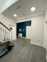 Hallway at Eilat with grey wood-effect flooring, a teal feature wall and white doors