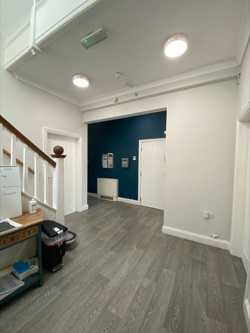 Hallway at Eilat with grey wood-effect flooring, a teal feature wall and white doors