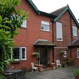 Red-brick rear exterior of Malvern View with a patio, white garden chairs and table