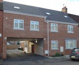 Front exterior of Glebe Road, a modern brick building with an archway car port and dormer windows