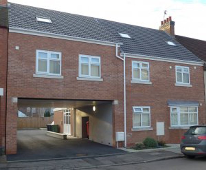 Front exterior of Glebe Road, a modern brick building with an archway car port and dormer windows