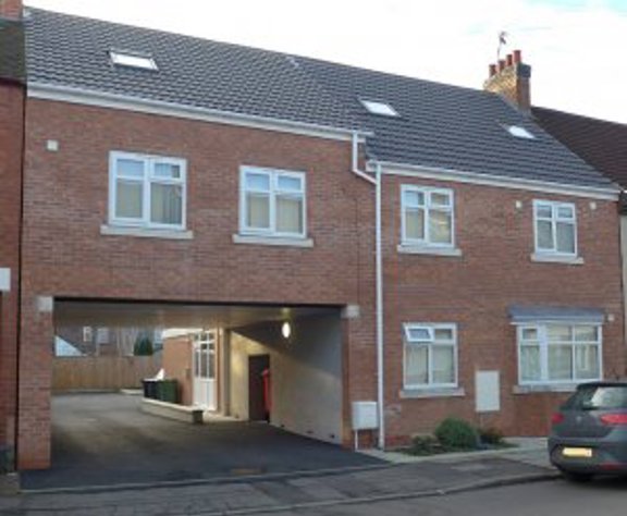 Front exterior of Glebe Road, a modern brick building with an archway car port and dormer windows