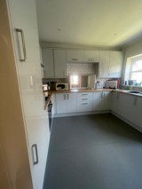 Kitchen at Rosewood with white gloss units, wooden worktops, a microwave and a grey floor