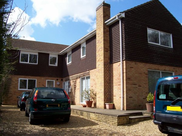 Two-storey brick and timber-clad exterior of Orchard View with a gravel driveway and parked cars