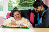 A support worker helping a resident prepare a salad at a table at Eilat