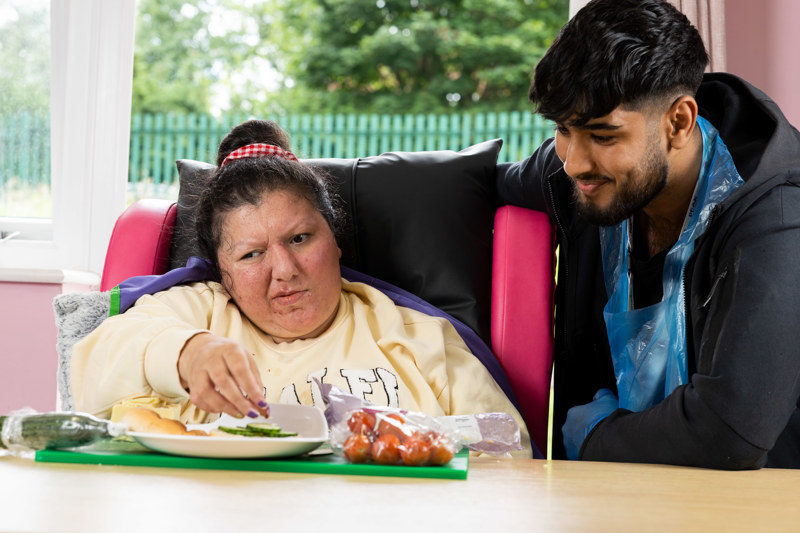A support worker helping a resident prepare a salad at a table at Eilat
