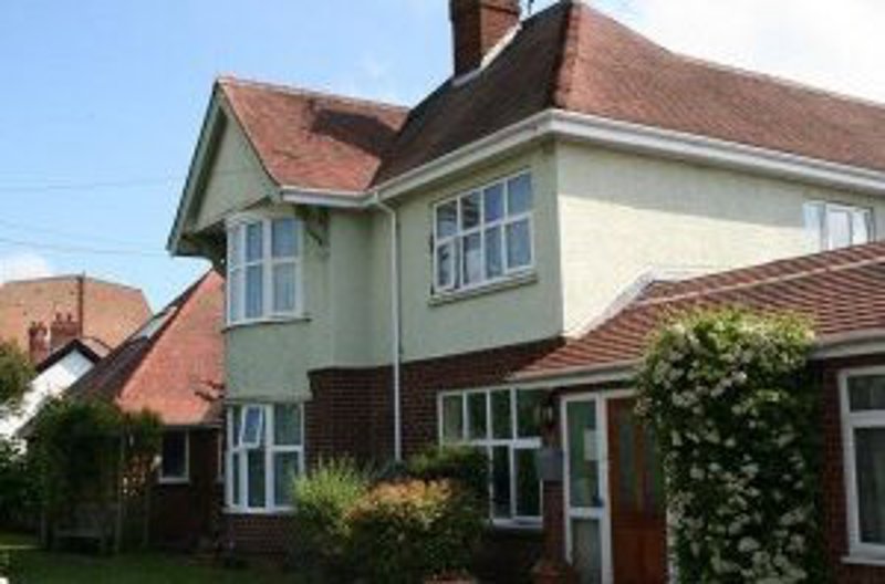 Exterior of Sunnydale, a rendered house with red-brick bay windows, a tiled roof and a small front lawn