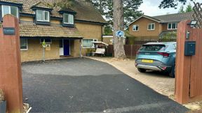 Driveway and front of Pinetrees seen from the gate, with the Pinetrees name sign and a parked car