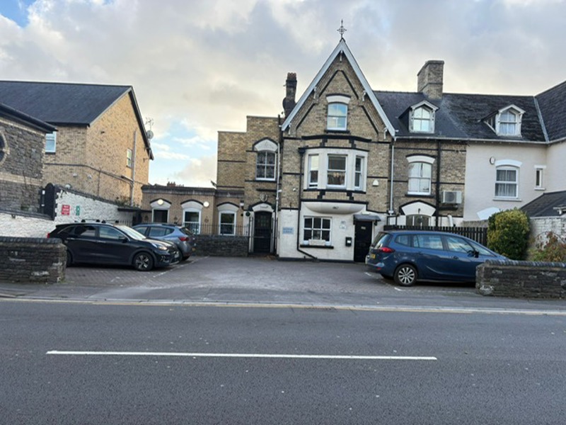 Street view of Manor Lodge from the main road with parking and parked cars