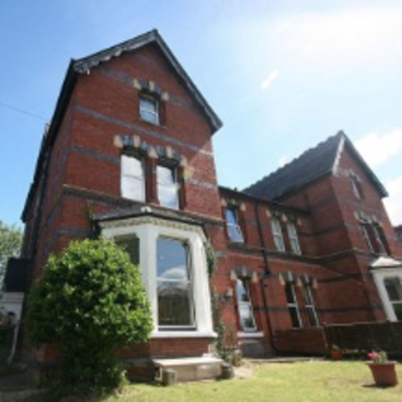 Red-brick Victorian exterior of Blackwells with bay windows and a front garden
