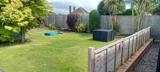 Enclosed back garden with lawn, wooden fencing and palm trees at Clairmont family assessment centre