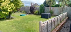 Enclosed back garden with lawn, wooden fencing and palm trees at Clairmont family assessment centre