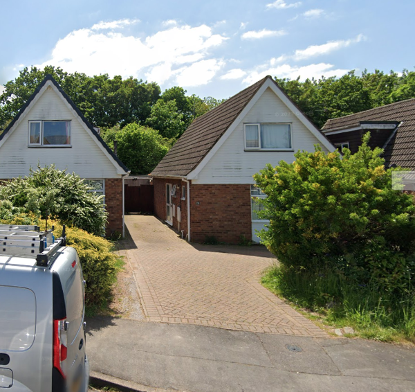 Street view of Conway Drive, a detached chalet-style house with brick and white cladding and a block-paved driveway
