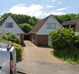 Street view of Conway Drive, a detached chalet-style house with brick and white cladding and a block-paved driveway