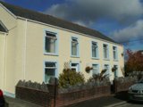 Front exterior of Rose Cottage, a cream-rendered two-storey house behind a low stone wall