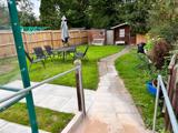Back garden at Chesterwood with a paved path to a summer house, lawn and patio seating