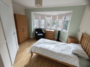 Bedroom at Evergreen with green walls, a bay window, a double bed and oak wardrobe and drawers