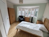 Bedroom at Evergreen with green walls, a bay window, a double bed and oak wardrobe and drawers