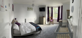 Spacious bedroom at Crown House with a double bed, baby cot and wooden rocking chair by a bay window
