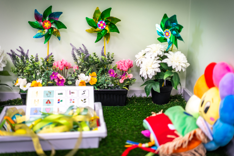Brightly coloured toys and plants on a bright green surface