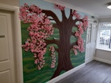 Hallway at Boston House with a hand-painted pink cherry blossom tree mural beside a glazed exit door