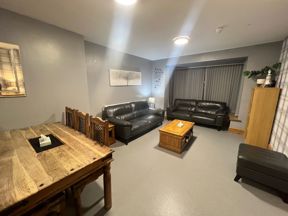 Lounge at Byron Lodge with black leather sofas, a wooden dining table and coffee table