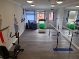 Rehabilitation gym at Boston House with an exercise bike, treadmill, parallel bars and an exercise ball
