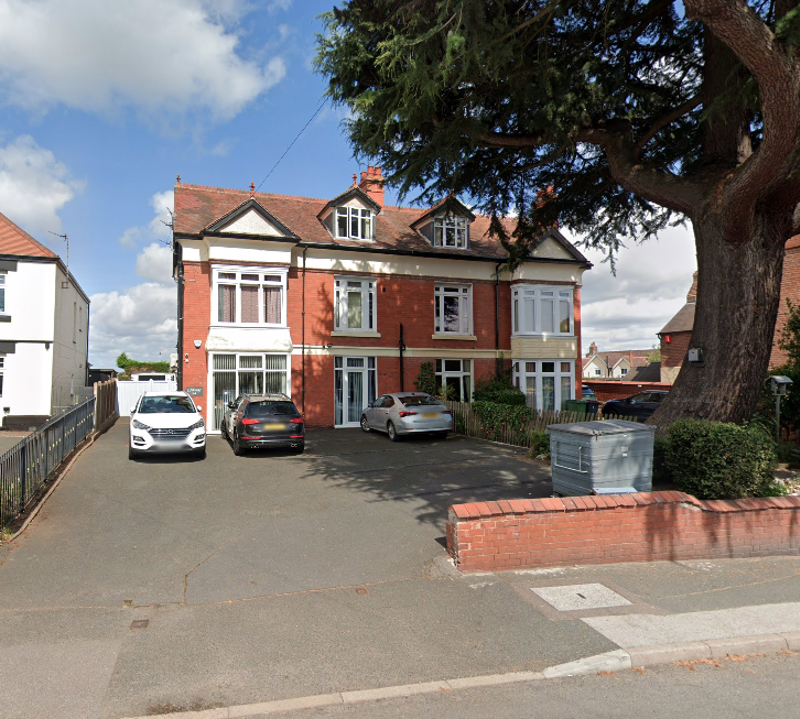 Red-brick double-fronted exterior of Clairmont family assessment centre with cars parked and a large tree