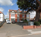 Red-brick double-fronted exterior of Clairmont family assessment centre with cars parked and a large tree
