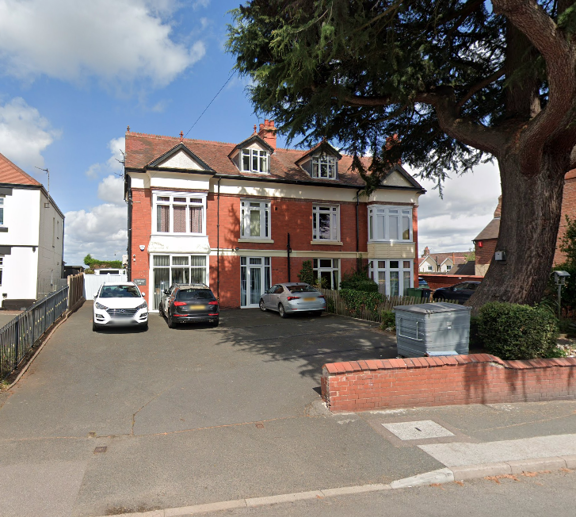 Red-brick double-fronted exterior of Clairmont family assessment centre with cars parked and a large tree