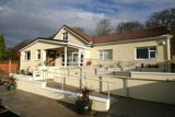 Cream rendered single-storey exterior of Oakhill with ramped railed access and potted plants